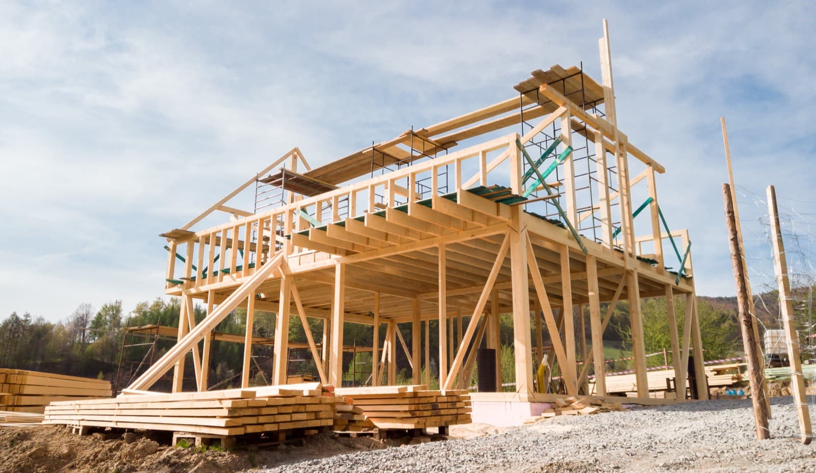 An all-wood post-frame building under construction, its posts, trusses, and roof framing going up.